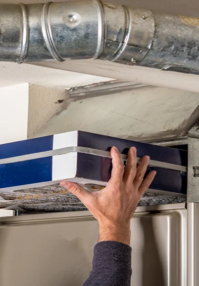 Hand replacing a home HVAC air filter, demonstrating proactive HVAC maintenance in the Puget Sound region.