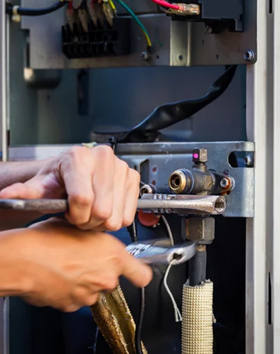 Close-up of HVAC technician adjusting furnace components, representing expert HVAC services in the Puget Sound area.