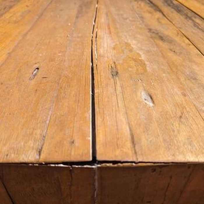 Close-up of dry, cracked hardwood floorboards with visible gaps due to low humidity.
