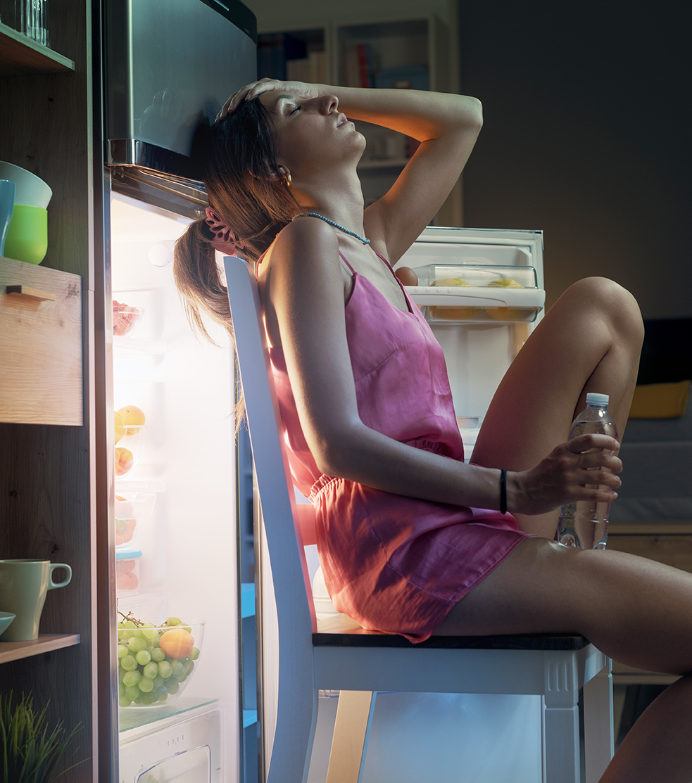 Woman sleeping by open refrigerator